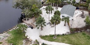 Ein Haus mit Terrasse, das auf ein Gewässer mit Blick blickt, umgeben von Palmen und einem Sandstrand.