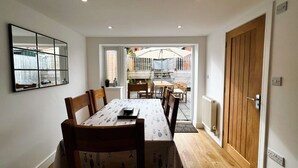 Un espace repas comprenant une table et des chaises, une porte en bois et une vue sur l’extérieur.