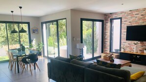 Un salon moderne comprenant un canapé, une table à manger, des chaises et un téléviseur.