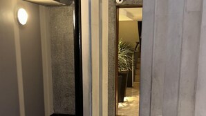 A modern hallway with a dark floor, a bench, and a light fixture on the left. - Departamento Amoblado Lloyd Apartment 94 (Bogotá)