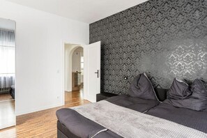 Een moderne slaapkamer met een groot bed, een donker hoofdbord en behang met een patroon.