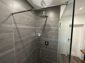 Een moderne douche met een handdouche en een kraan op de muur.