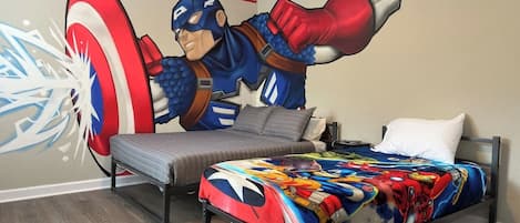 Una camera da letto con un letto, una panca e un affresco raffigurante un supereroe.