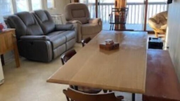 A spacious living room with a large wooden dining table, a grey sofa, and a wooden chair. - Brimfield Waterfront cottage (Brimfield)