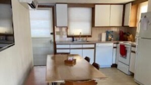 A compact kitchen with a wooden table and chairs, a refrigerator, and a stove. - Brimfield Waterfront cottage (Brimfield)