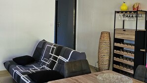 Ein Wohnzimmer mit einer Couch, einem Holzesstisch und einem dekorativen Regal mit Weingläsern.