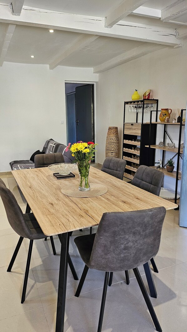 A dining area with a wooden table, grey upholstered chairs, and a vase with yellow flowers.