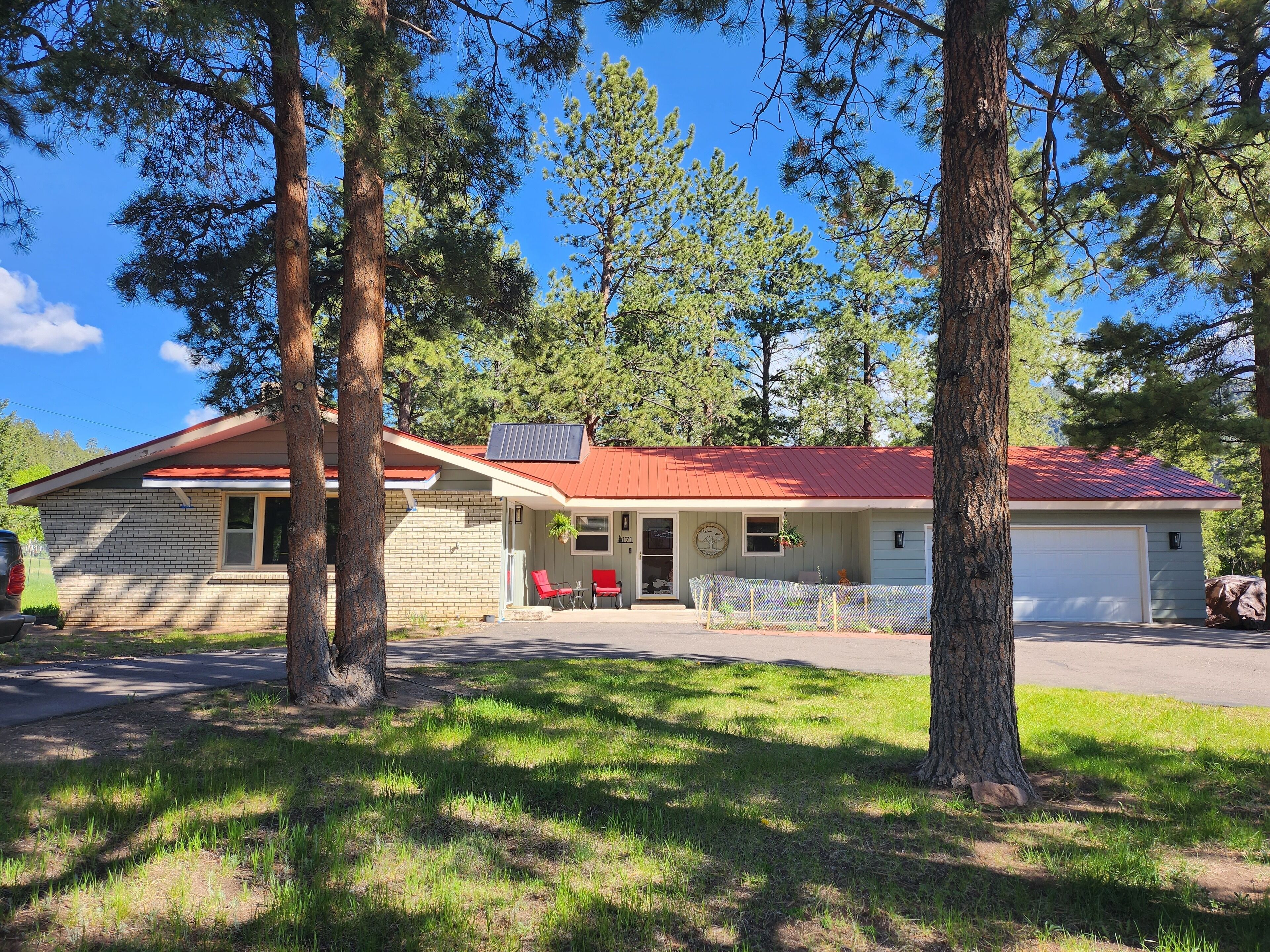 A two-story building with a red roof, a covered porch, and a garage.