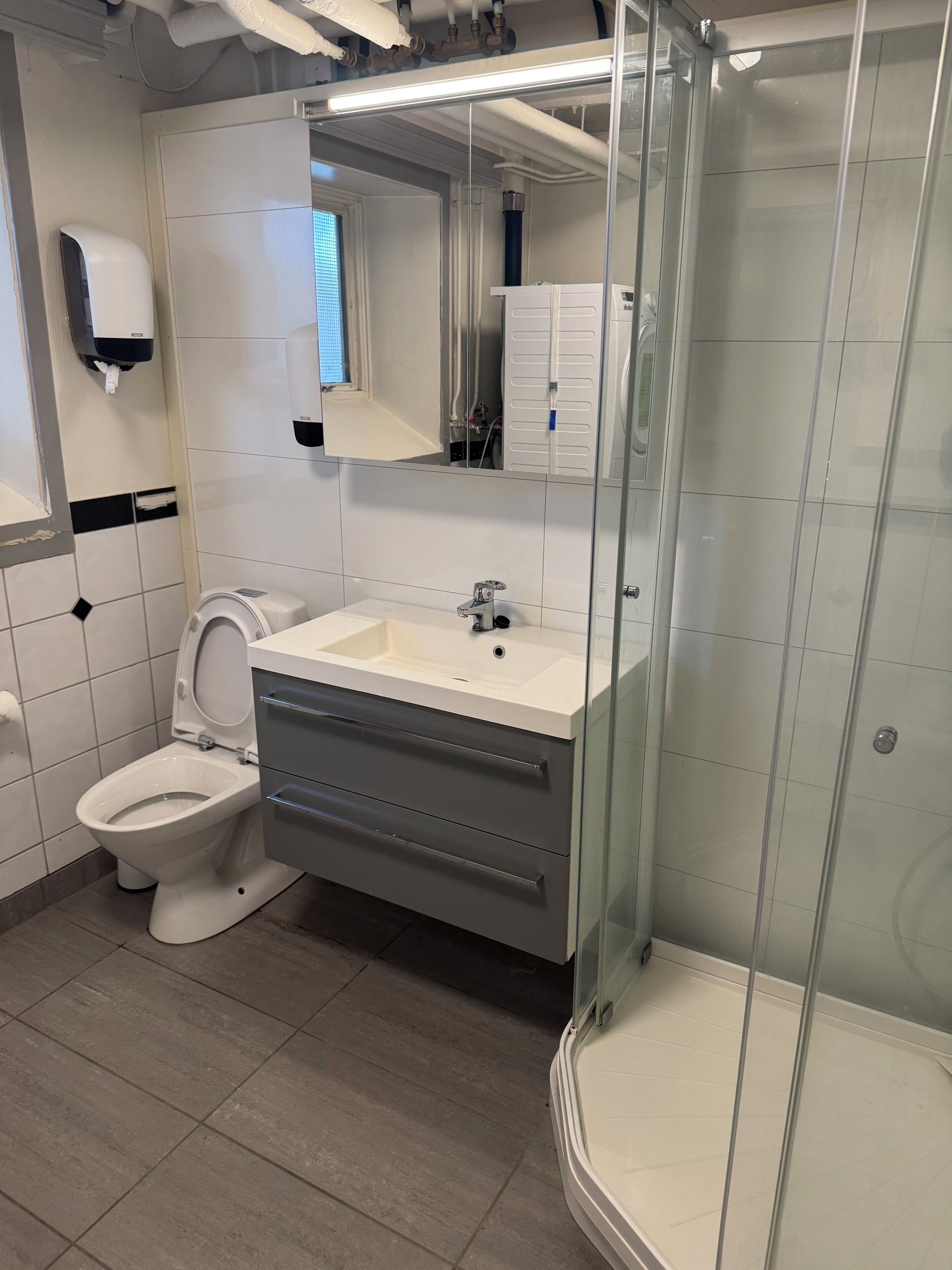 A modern bathroom with a toilet, sink, and glass-enclosed shower.