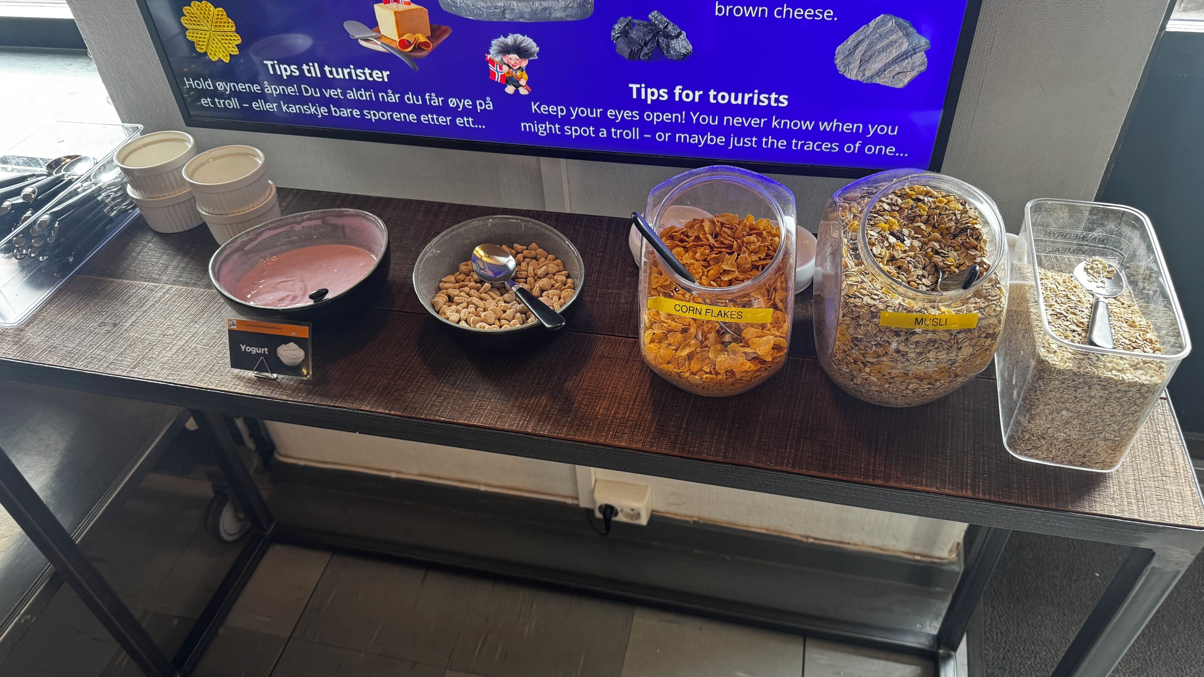 A snack bar with yogurt, corn flakes, musli, and brown cheese.