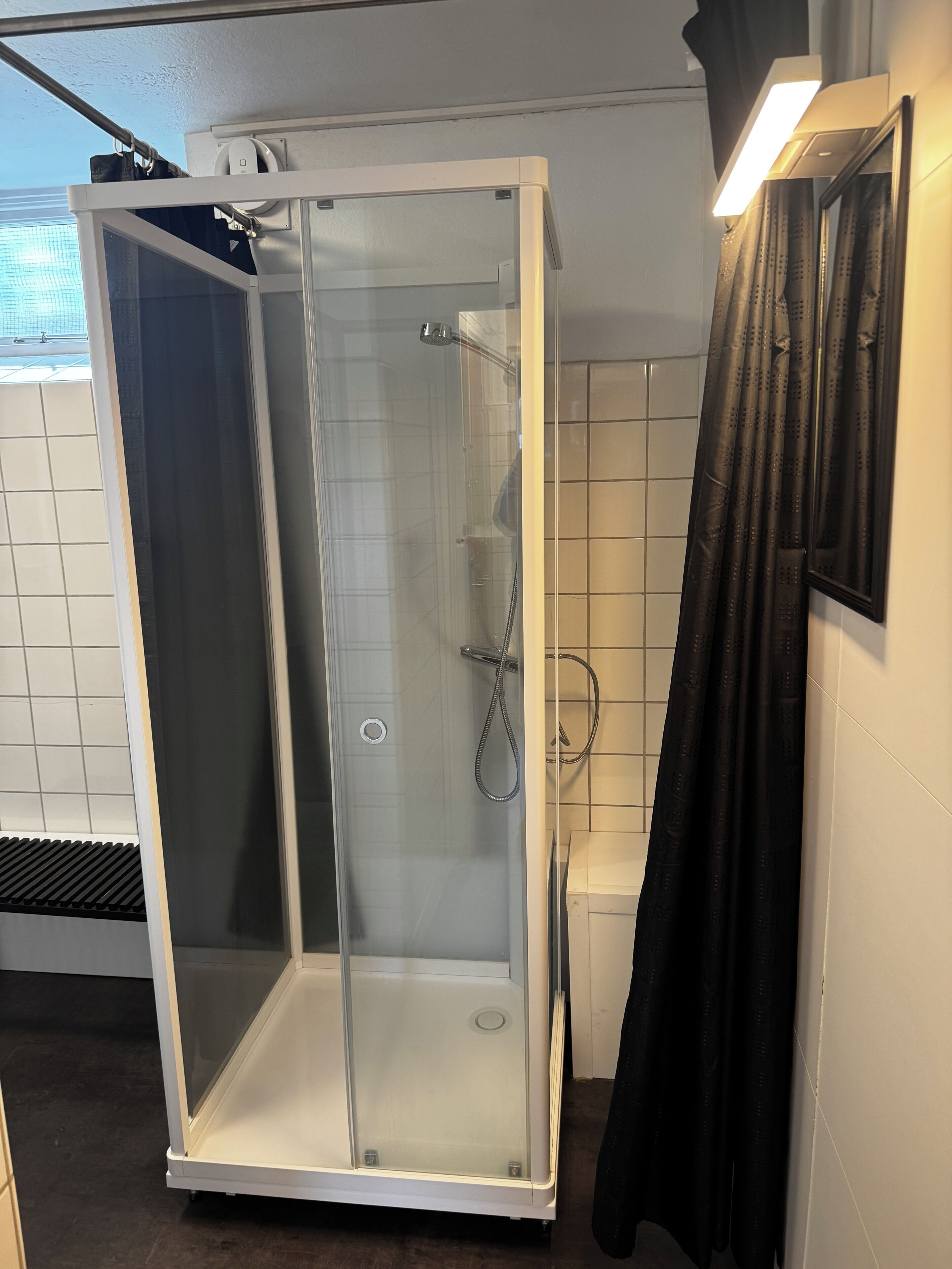 A walk-in shower with a glass door, a showerhead, and a hand shower.