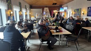 A restaurant with tables and chairs, a reception desk, and a wall with various items displayed. - Sjømannskirken Hostel (Narvik)