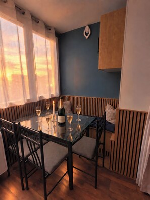Comedor con mesa de vidrio dispuesta para seis personas, una botella de champán y velas.