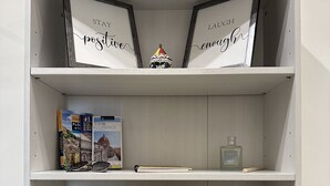 A bookshelf with framed signs, books, a decorative lamp, and a basket with flowers. - Bright cozy apartment in the CITY CENTER of the city heart of the Renaissance (Firenze)