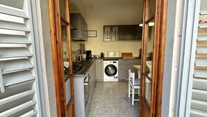 A narrow hallway leading to a kitchen with a washing machine, a microwave, and wooden cabinets. - Bright cozy apartment in the CITY CENTER of the city heart of the Renaissance (Firenze)