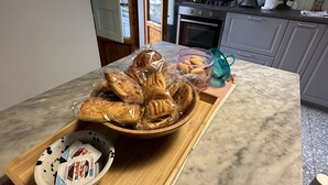 A kitchen with a marble countertop, a wooden serving tray with pastries, a Nutella jar, and a window with a view of buildings. - Bright cozy apartment in the CITY CENTER of the city heart of the Renaissance (Firenze)