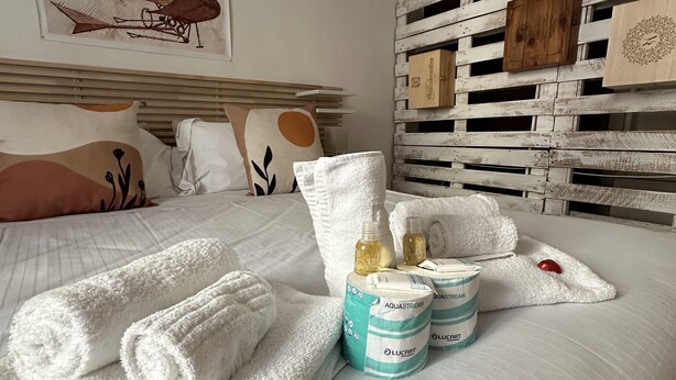 A neatly made bed with white towels, a red heart-shaped pillow, and two bottles of Aquastream and Lucart bath products. - Bright cozy apartment in the CITY CENTER of the city heart of the Renaissance (Firenze)