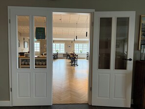 A hotel lobby with a herringbone floor, a reception desk, and a dining area with tables and chairs. - Hotel Stafholt (Borgarbyggd)