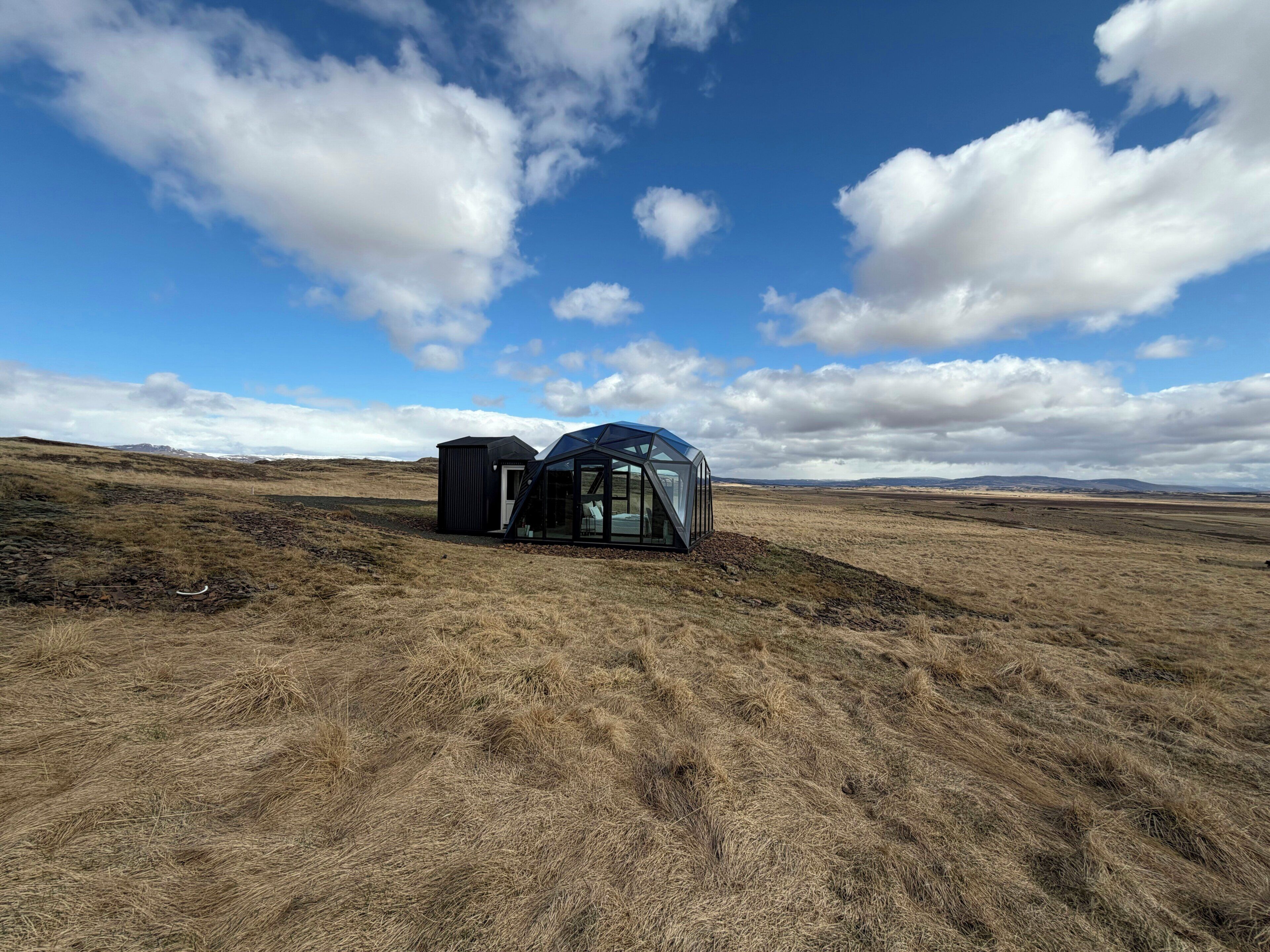 A remote, open landscape with a modern, glass-enclosed structure.
