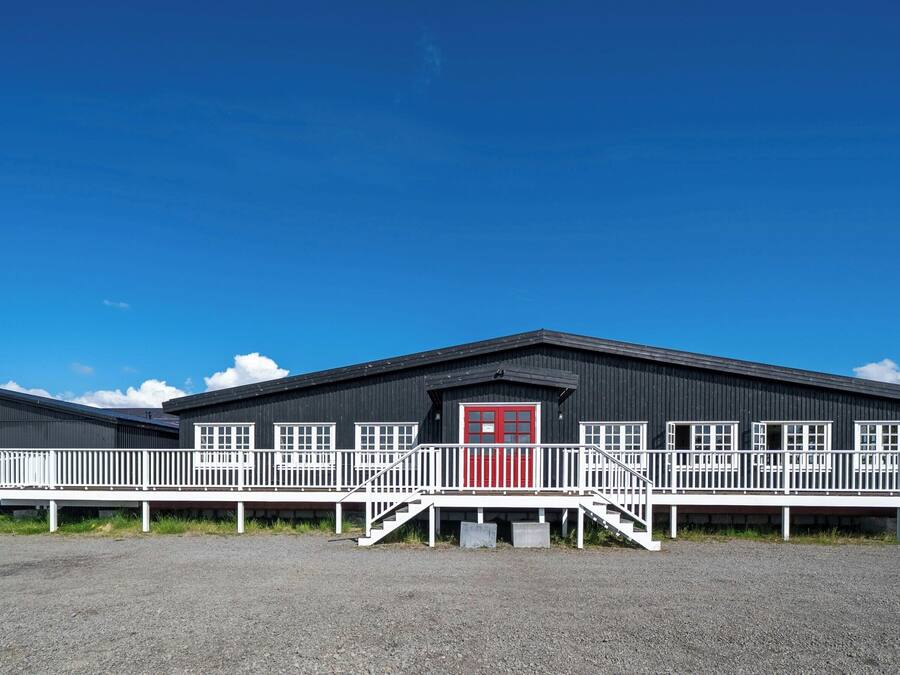 A building with a red door, white railings, and a gravel ground.