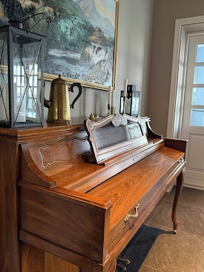A wooden desk with drawers, a brass coffee pot, a framed painting, and a lantern. - Hotel Stafholt (Borgarbyggd)