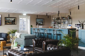 A bar area with seating, a sofa, and a coffee table in a modern interior.