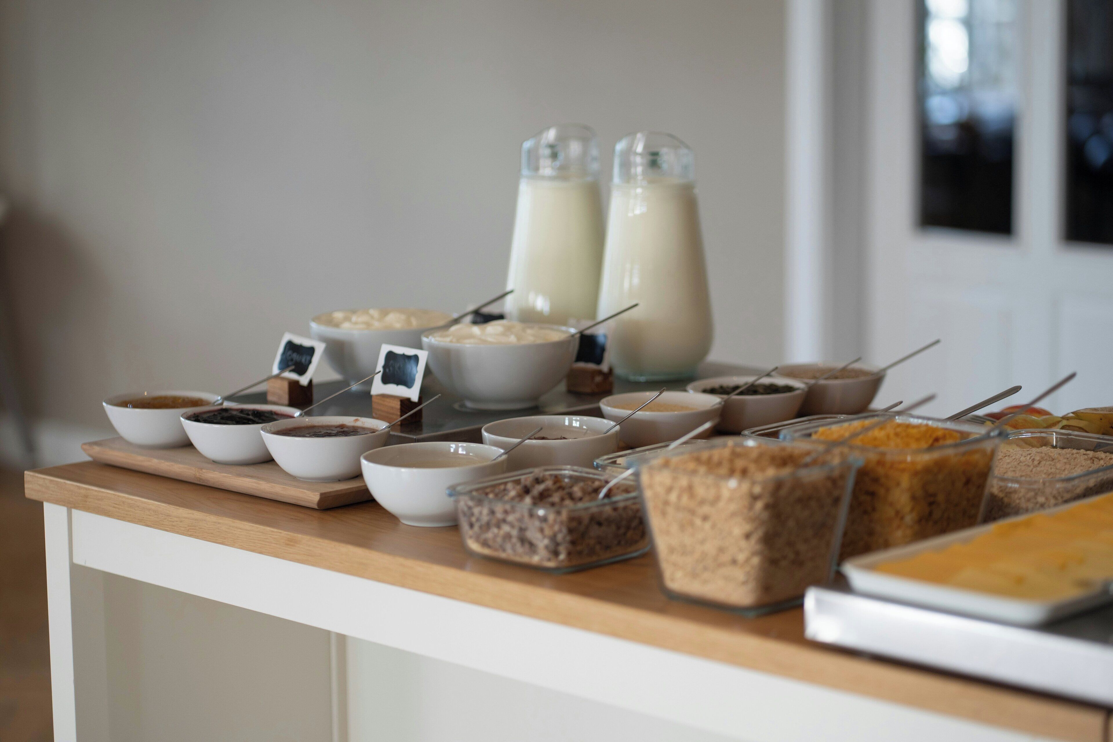 Un bufé con diversos alimentos y dos botellas de leche sobre una mesa de madera.