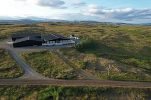 A large building with a sloped roof, a paved driveway, and a small parking area. - Hotel Stafholt (Borgarbyggd)