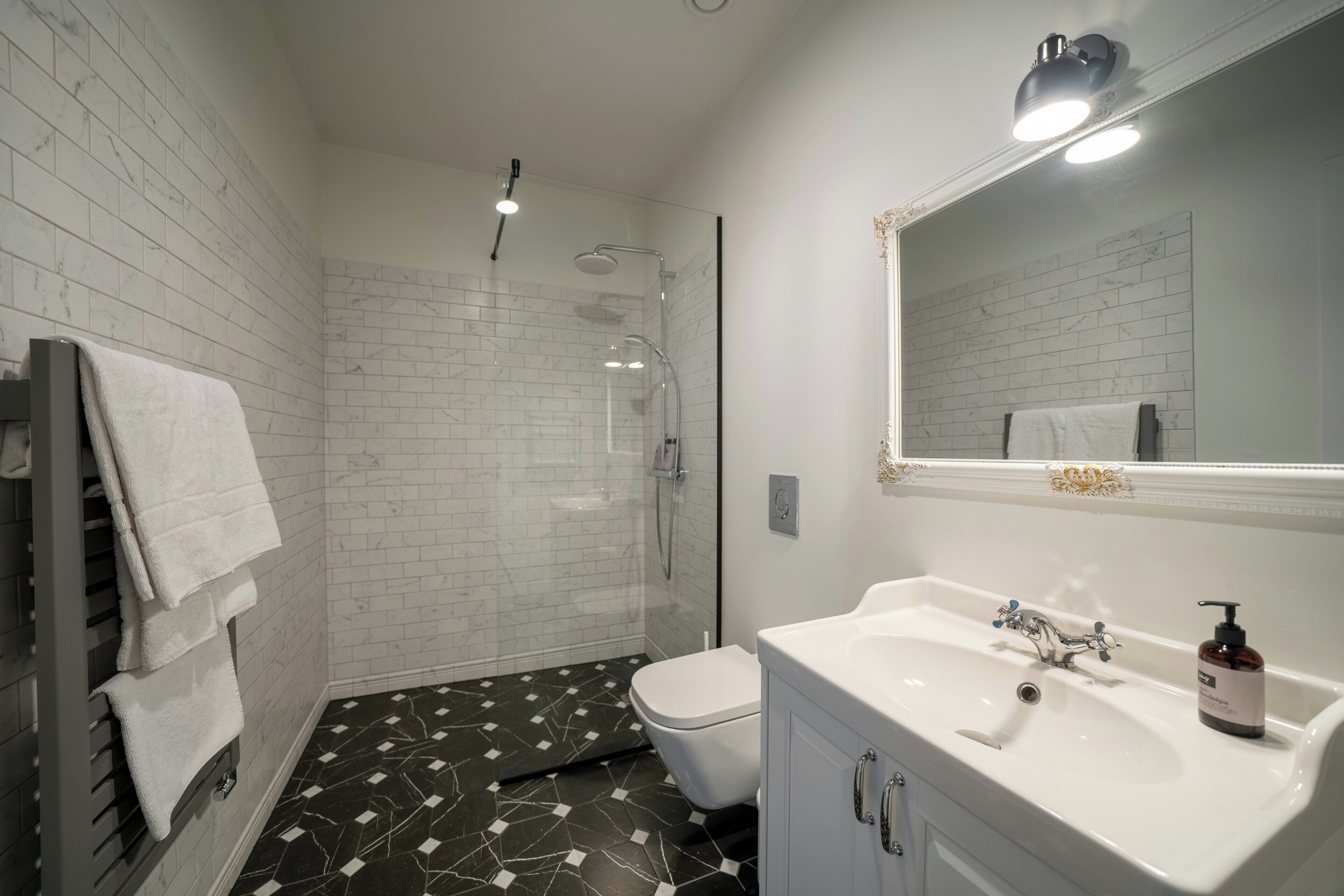 Un baño con un lavamanos blanco, un espejo, una ducha y un inodoro.