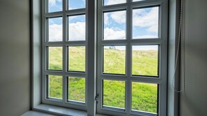 A window with a view of a grassy field and a clear sky. - Hotel Stafholt (Borgarbyggd)
