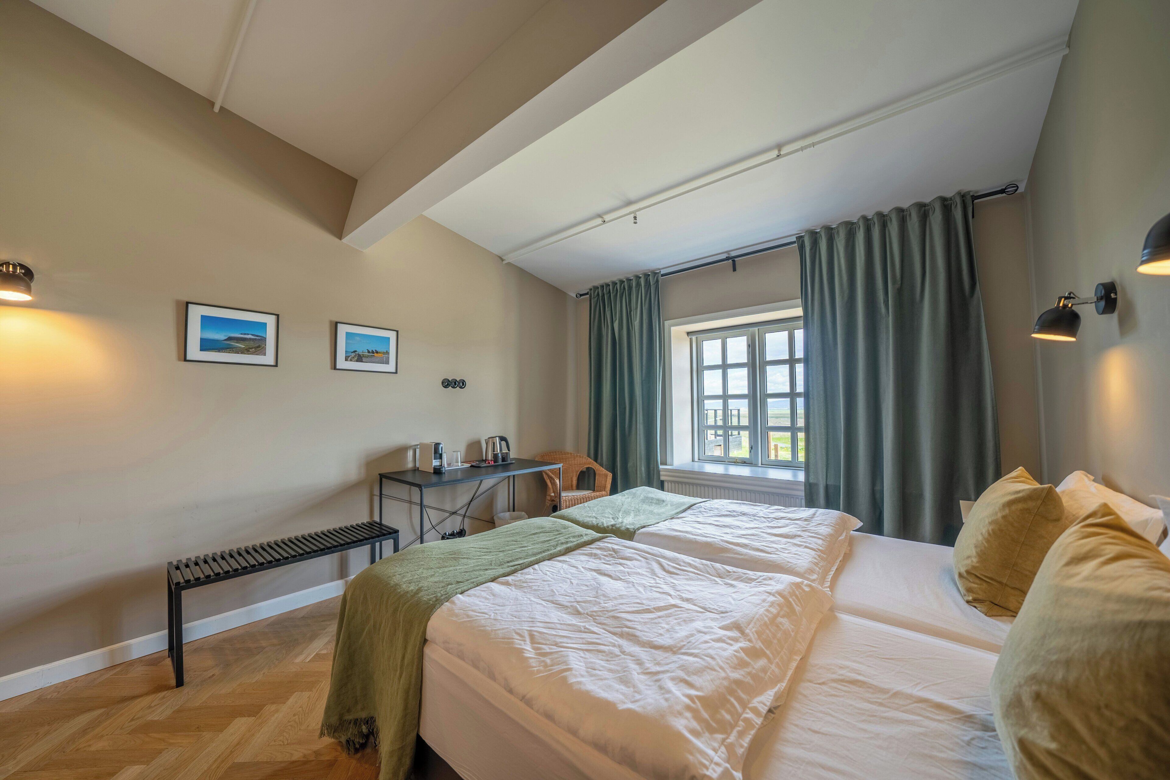 A bedroom with a bed, a desk, a chair, and a window with curtains.
