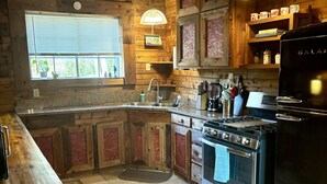 Una cocina rústica con armarios de madera, una estufa de acero inoxidable y un ventanal.