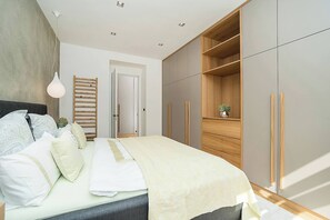 A bedroom with a bed, bedside tables, a wardrobe, and a hanging light fixture.