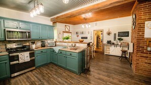 A kitchen with teal cabinets, a stainless steel microwave, and a wooden island.