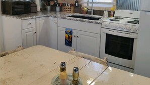 A kitchen with a stove, sink, and microwave. There is a window with blinds and a towel hanging on the door. - Bigfoot themed cottage.  Dog friendly! (Harrison)