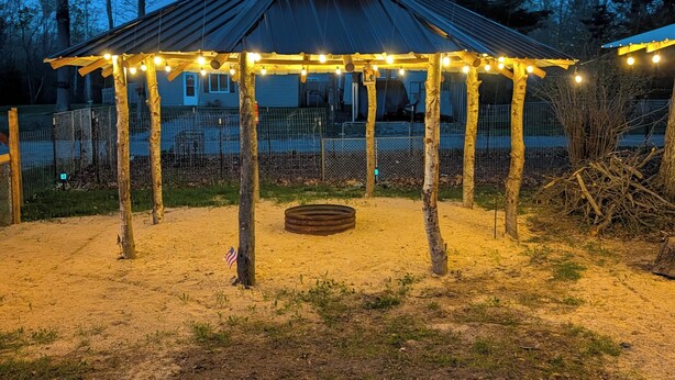 A gazebo with a metal roof and wooden posts, surrounded by a fenced area with a sandy ground. - Bigfoot themed cottage.  Dog friendly! (Harrison)