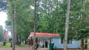 A small, single-story building with a red roof, surrounded by trees. - Bigfoot themed cottage.  Dog friendly! (Harrison)