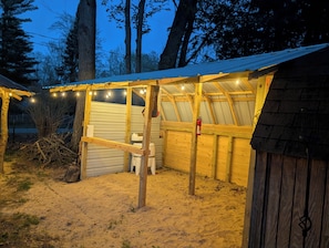 A wooden structure with a metal roof, string lights, and a fire extinguisher.