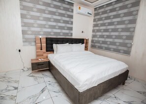 Relax in a serene bedroom with a large bed and stylish window treatments.