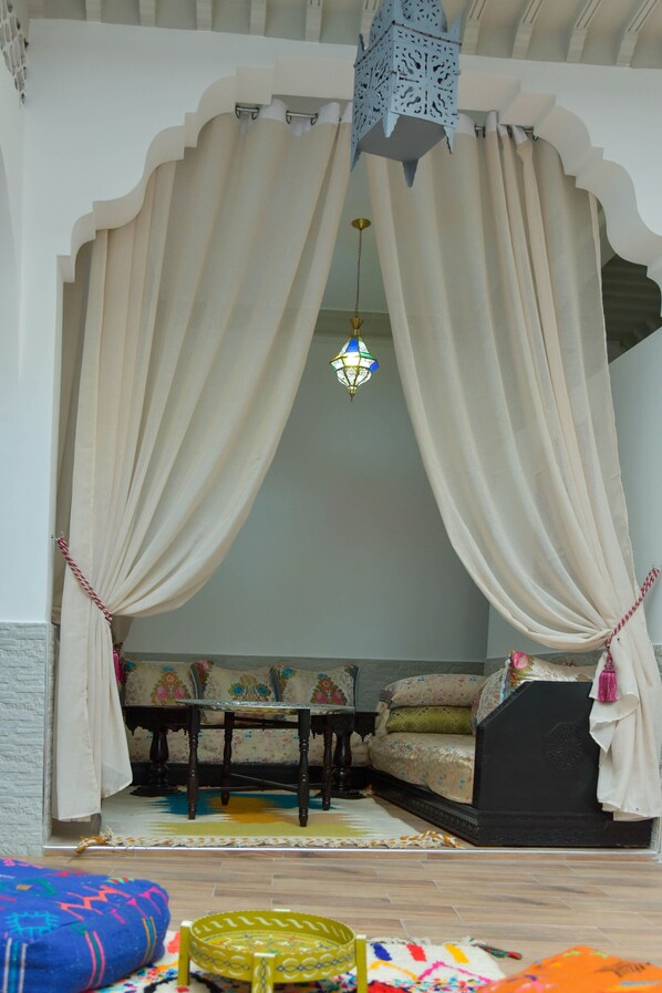 A room with a bed, a table, and a colorful rug.