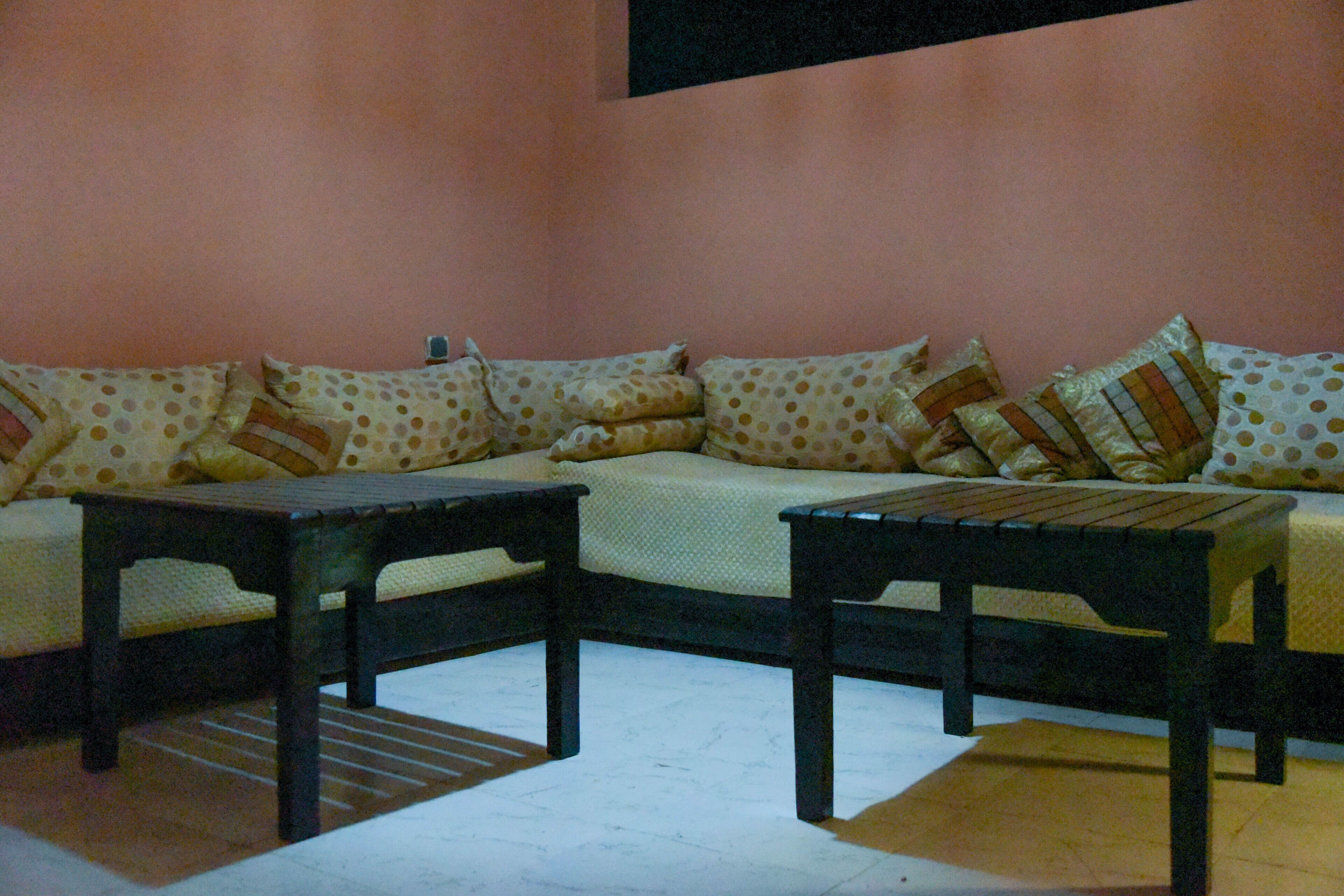 A living room with a sofa set, two wooden side tables, and a patterned throw pillow.