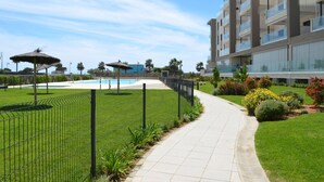 A modern hotel with a swimming pool, a well-maintained lawn, and a pathway leading to the pool area.