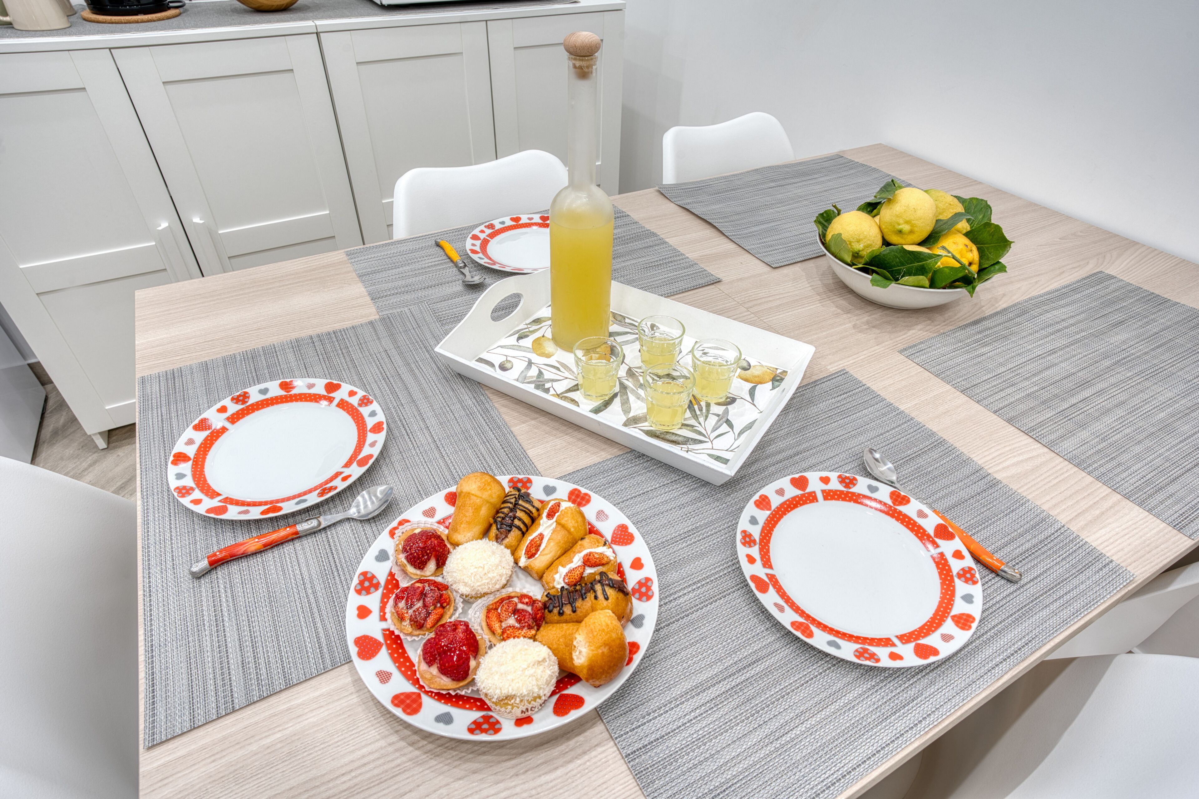 Een eettafel met borden vol gebak en een fles citroenlimonade.