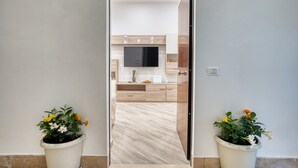 A modern kitchen with wooden cabinets, a flat-screen TV, and a potted plant. - Margaret House Sorrento (Sorrento)
