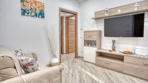 A modern living room with a sofa, a flat-screen TV, and a wooden cabinet. - Margaret House Sorrento (Sorrento)