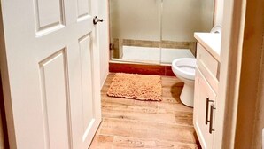 Een badkamer met een douchecabine van glas, een toilet en een wastafel.