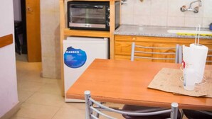 A compact kitchen with a built-in oven, a small refrigerator, and a sink.