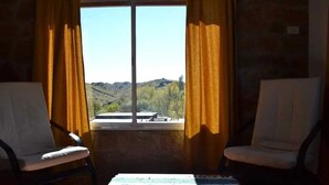 A room with two chairs, a table, and a window with curtains.