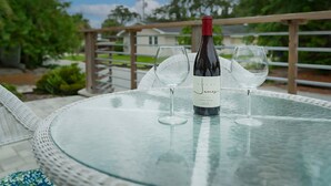 A bottle of wine on a glass table with two wine glasses. - Downtown Dunedin Cottage • Walk to Restaurants (Dunedin)