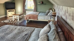 Ein Schlafzimmer mit zwei Betten, einem Fernseher, einem kleinen Tisch und einem Fenster mit Vorhängen.